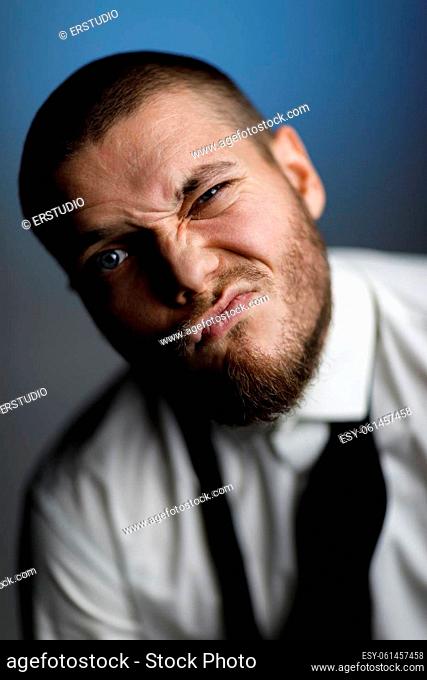 emotional male portrait. doubting bearded man in white shirt and untied bow tie