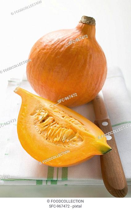 Hokkaido pumpkins whole and quarter on tea towel, knife
