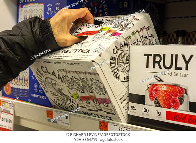 A discerning consumer chooses a case of White Claw brand hard seltzer among other brands in a cooler in a supermarket in New York on Monday, May 13, 2019