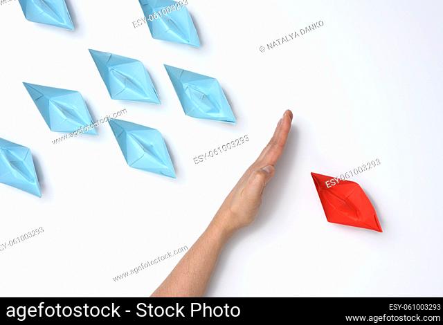 female hand between paper boats on a white background, concept of reconciliation of the parties, the search for compromises