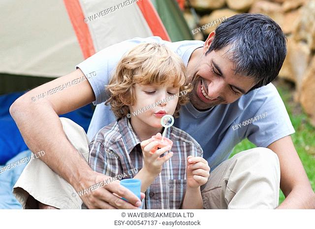 Father and son having fun with bubbles in a tent