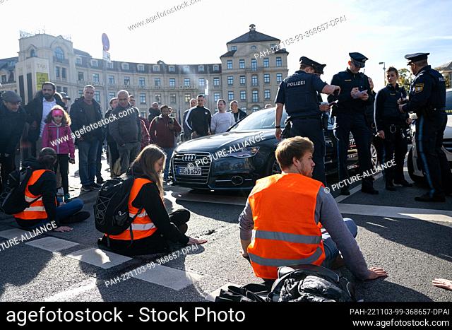 03 November 2022, Bavaria, Munich: Climate activists have stuck themselves on the roadway at Karlsplatz in downtown Munich, blocking the street