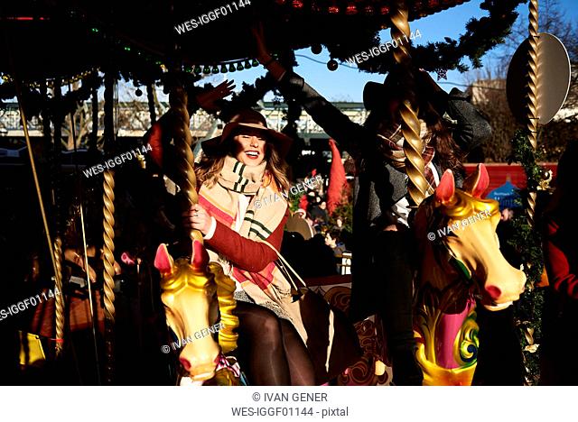 Two happy women having fun on a carousel