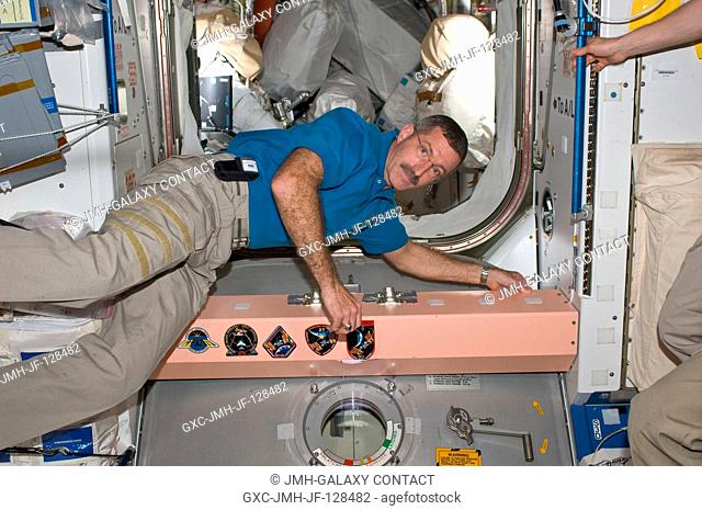 In the Unity node, NASA astronaut Dan Burbank, Expedition 30 commander, is pictured near the growing collection of insignias representing crews who have worked...