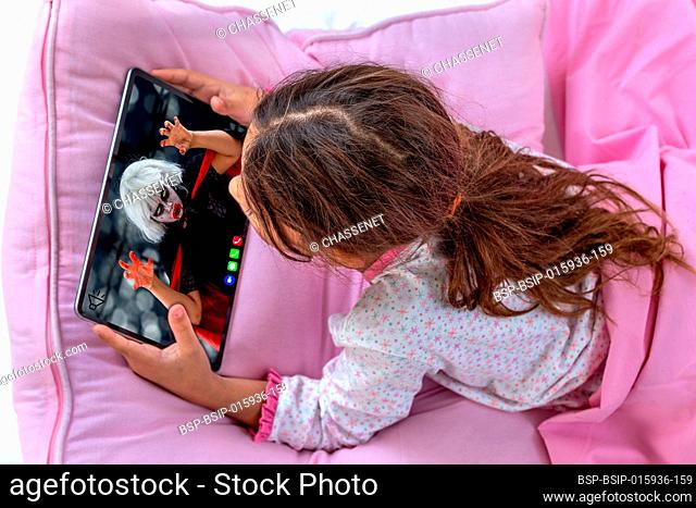 Little girl using digital tablet and playing in bed
