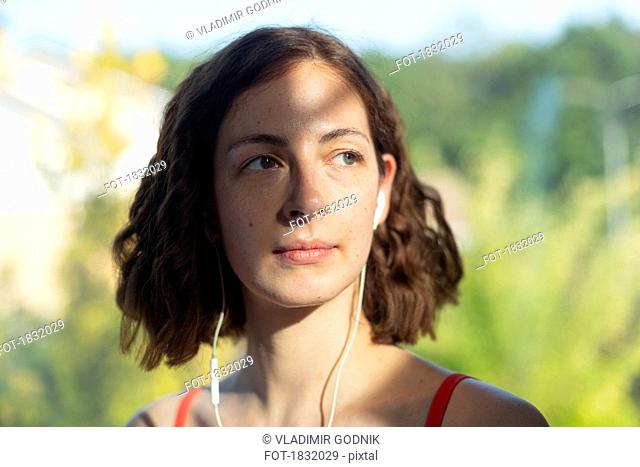 Thoughtful woman listening to music with headphones