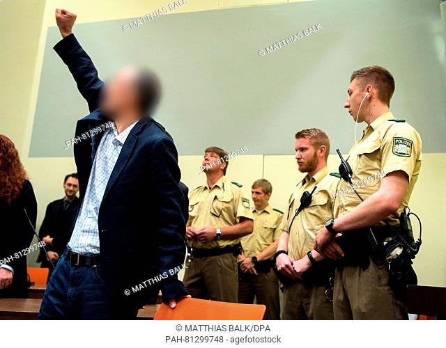 Muslum E. (r), accused of the membership in a foreign terror group, greets the visitors of the trial in a courtroom at Higher Regional Court in Munich, Germany