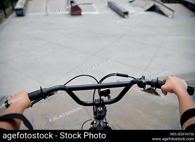 Boy holding handlebar of BMX bike at sports ramp