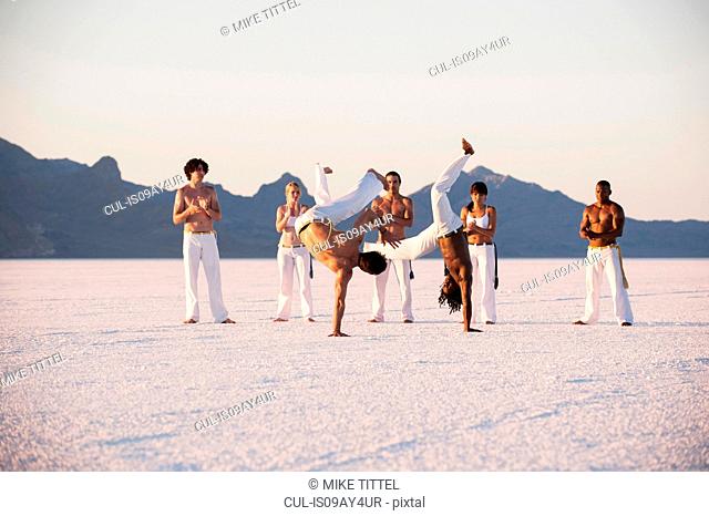 Team clapping man performing capoeira on Bonneville Salt Flats, Utah, USA