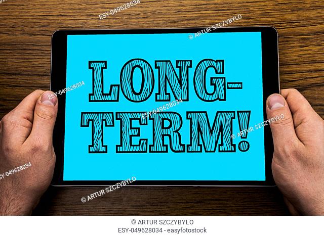 Text sign showing Long-Term Motivational Call. Conceptual photo Occurring over large period of time Future plans written Tablet Screen holding in Hand wooden...