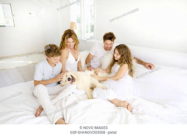 Happy Family Laying on Bed with Pet Dog