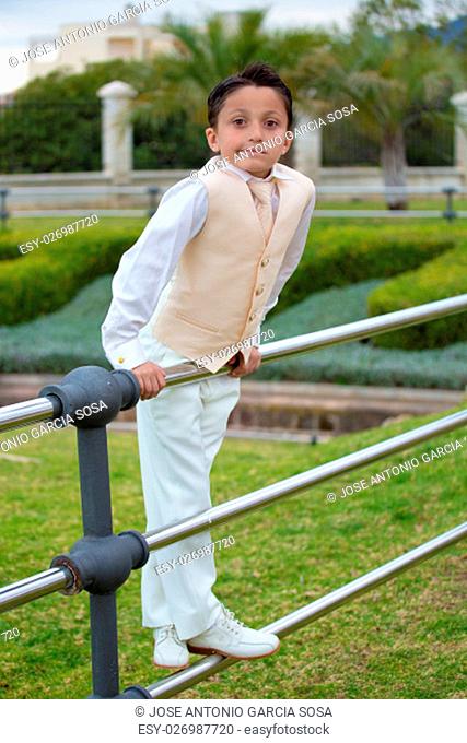 Young boy leaning on a metal fence in his First Communion