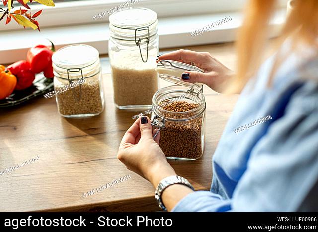 Women opening jar with seeds in kitchen