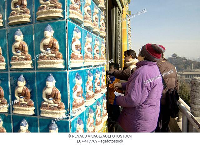Rows of glazed tiles of Buddha decorating the Temple for Cultivating Good Deeds in front of the White Dagoba in Beihai Park. Beijing. China