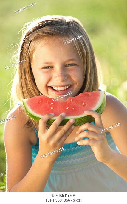 Young girl eating a slice of watermelon