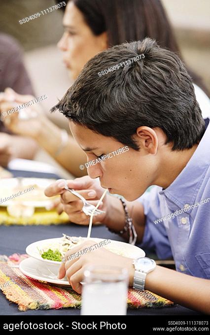 Teenage boy eating pasta
