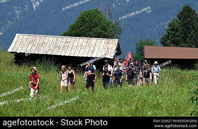 27 June 2022, Bavaria, Garmisch-Partenkirchen: Activists protesting against the G7 summit walk in a star march along one of the four routes to the G7 meeting...