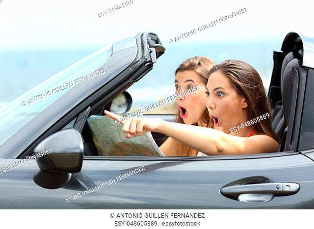 Amazed girls in a car pointing away on summer vacations