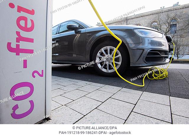 18 December 2019, Lower Saxony, Hanover: An electric car from Audi is charged with a cable at an e-charging station with the inscription ""Co2-free""