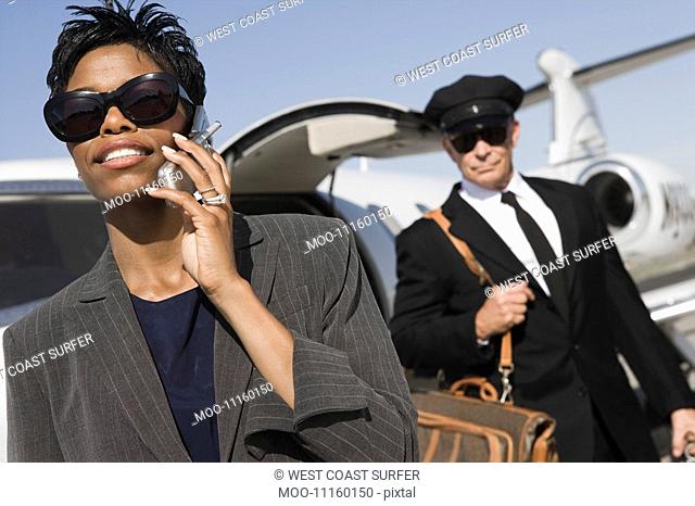 Mid-adult businesswoman talking on phone while chauffeur is waiting