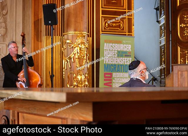 08 August 2021, Bavaria, Augsburg: A visitor wearing a kippah sits in the golden hall of the town hall before representatives of various religious communities...