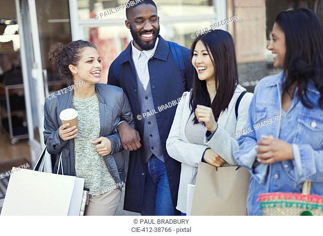 Smiling friends with coffee and shopping bags