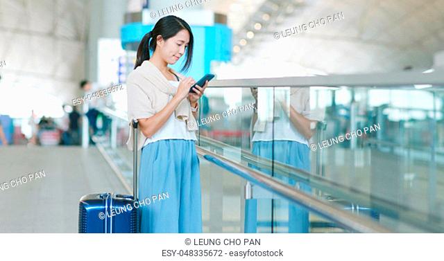Woman checking flight number on cellphone in the airport