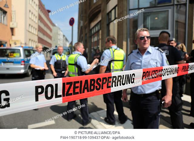 18 July 2019, North Rhine-Westphalia, Cologne: Policemen are standing in front of a residential building in the city centre behind a barrier tape