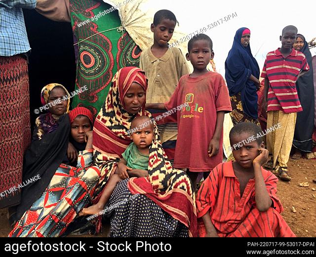 28 June 2022, Somalia, Baidoa: Salado sits with her children in front of the family's makeshift hut. The family had to leave their home village because of the...