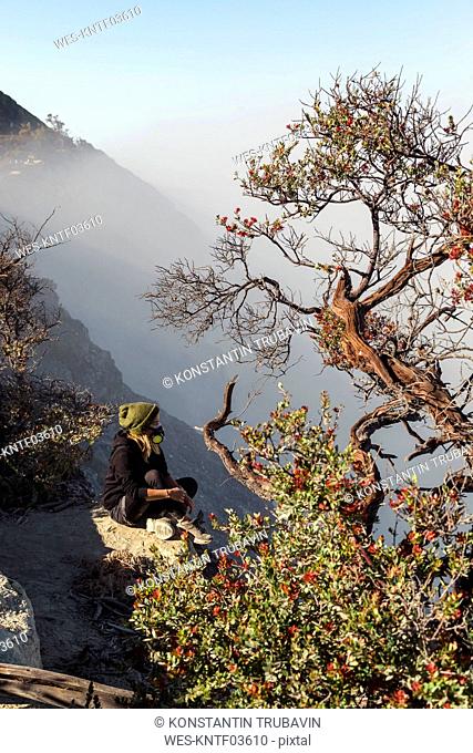 Woman with respirator mask sitting at volcano Ijen, Java, Indonesia