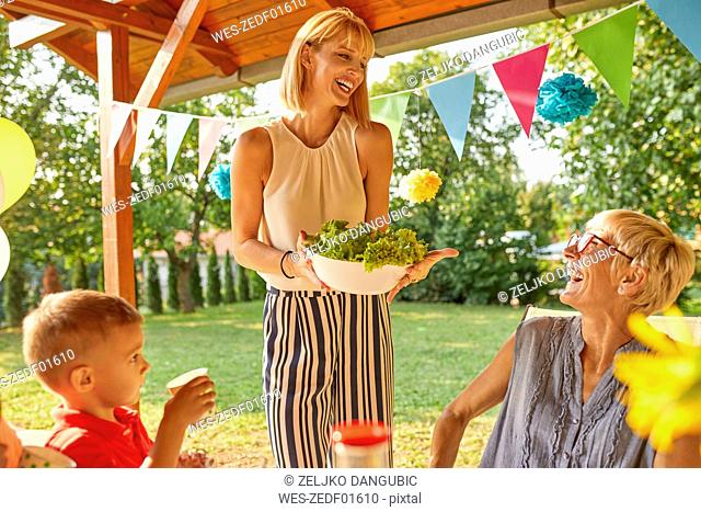 Happy woman serving salad on a garden party