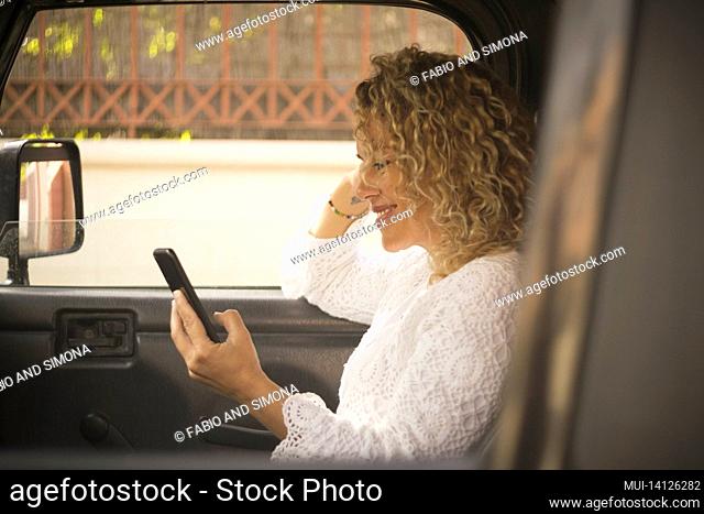 beautiful woman text messaging or watching media content using mobile phone sitting in car. happy woman with mobile phone in car