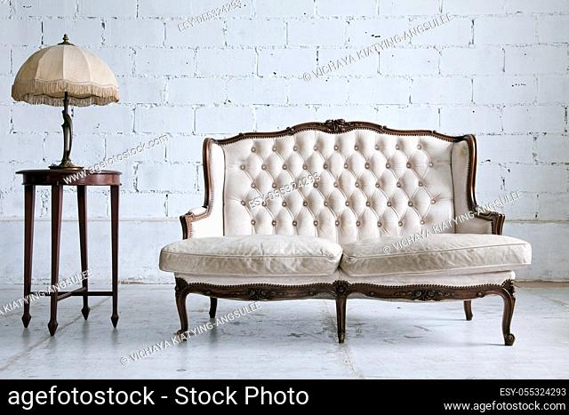 White genuine leather classical style sofa in vintage room with desk lamp