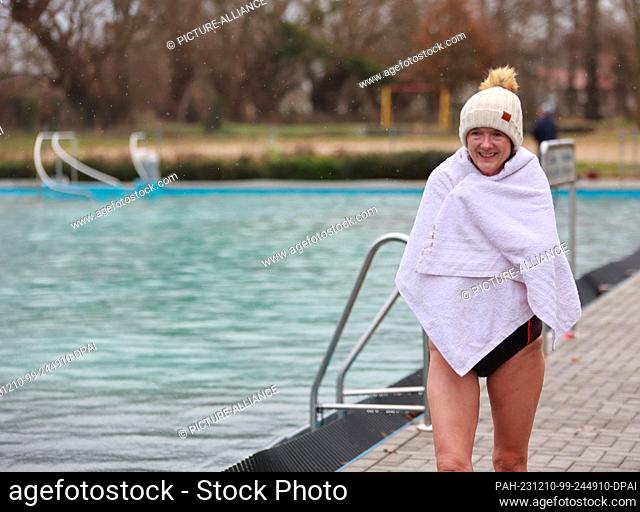 10 December 2023, Saxony-Anhalt, Osterwieck: A participant in the Advent swim enters the water at 6 degrees Celsius in the Osterwieck outdoor pool