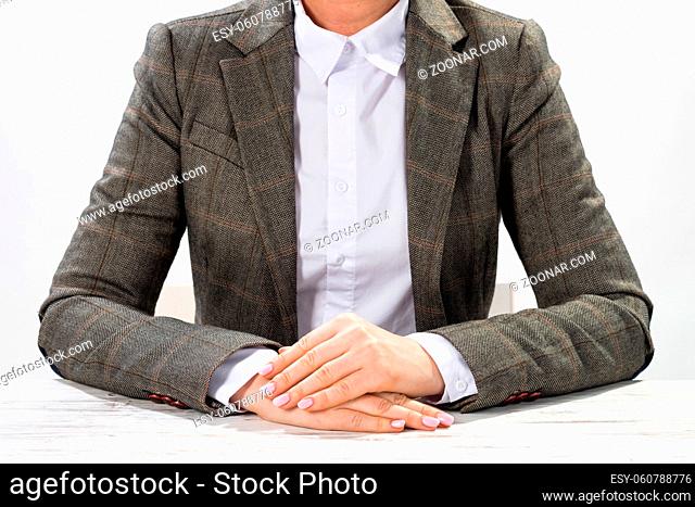 Close up businesswoman sitting at desk with folded arms. Concentrated business lady on background of white wall. Business consultation in office