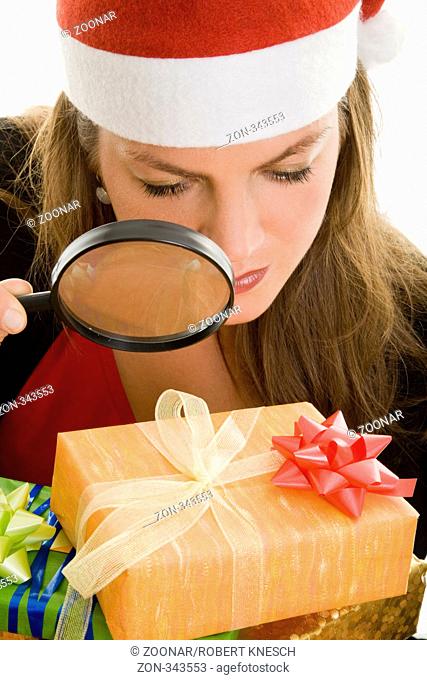 Frau mit Weihnachtsmütze kontrolliert mit einer Lupe Geschenke Model: Eva Lux