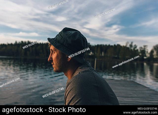 Young man with hat, looking at lake