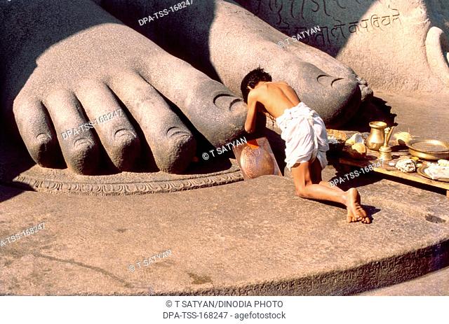 Pilgrim prostrates giant feet of gomateshwara statue at Sravanabelagola ; Karnataka ; India 1980 colossus