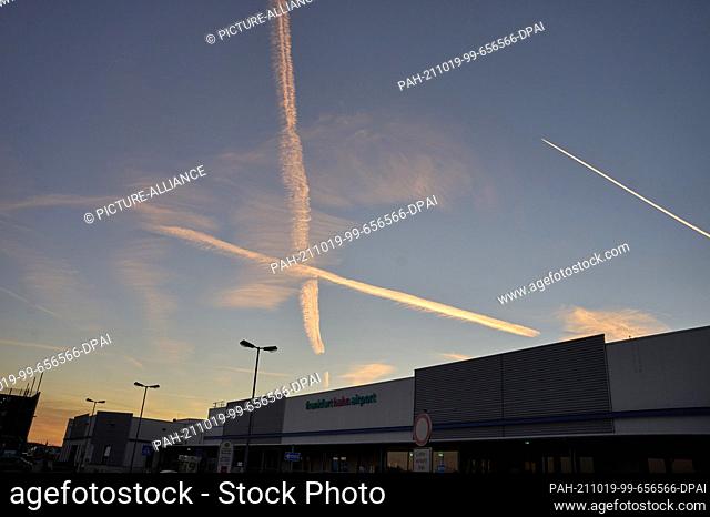 19 October 2021, Rhineland-Palatinate, Hahn: The vapour trails of two aircraft cross over the terminal of the former American military airport Hahn in Hunsrück