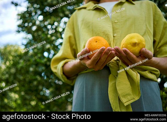 Woman holding citrus fruits standing in orchard