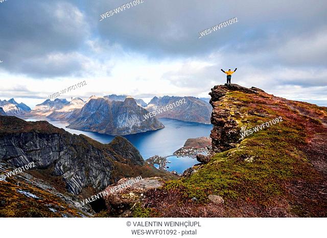 Norway, Lofoten Islands, Reine, Man with raised arms on Reinebringen