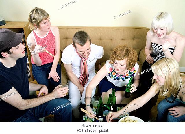 A group of friends eating and drinking in a living room