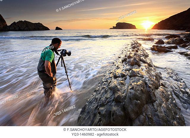 A photographer on beach at sunrise, La Arnía, Costa Quebrada, Piélagos, Cantabria, Spain