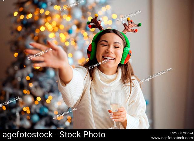 Beautiful young woman with glass of champagne at home. Christmas celebration