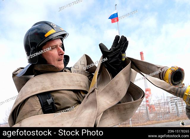 PETROPAVLOVSK CITY, KAMCHATKA PENINSULA, RUSSIA - APR 19, 2019: Firefighter-rescuer Emercom of Russia collects long fire hose on hands