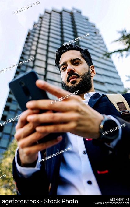 Businessman using mobile phone while standing in city