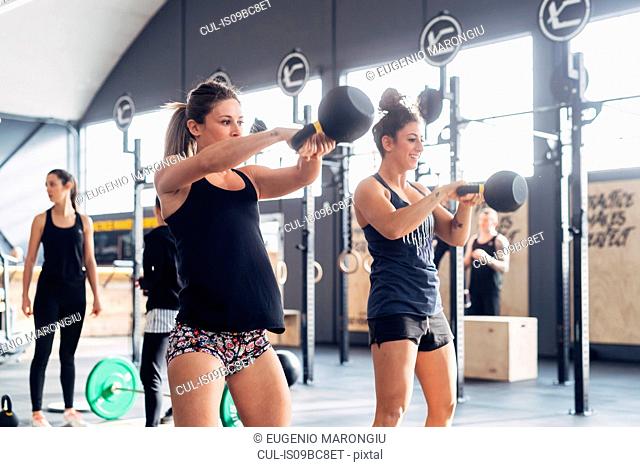 Woman weightlifting with kettle bells in gym