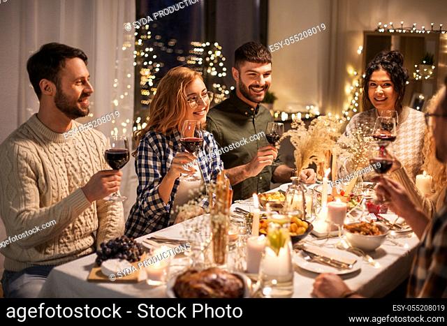 happy friends drinking red wine at christmas party