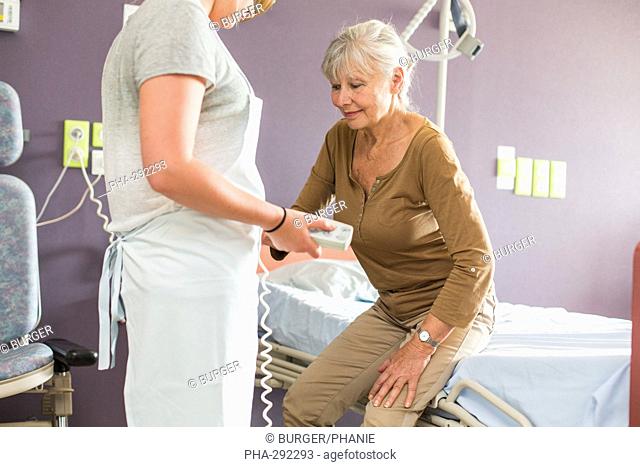 Ergonomic Equipment Disabled Room (PMR). Here woman using a remote control to adjust the height of a hospital bed facilitating the passage sit / stand