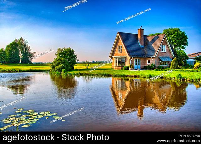 Red bricks house in countryside near the lake with mirror reflection in water, Amsterdam, Holland, Netherlands, HDR